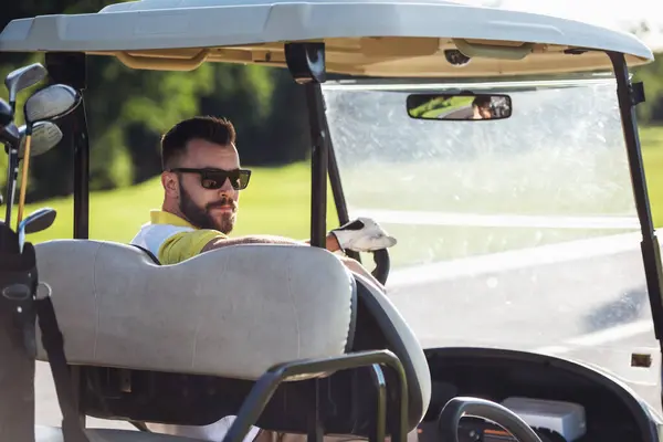 Handsome guy is looking at camera while driving a golf cart