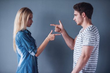 Güzel genç adam ve kadın el-silahlar her, gri arka plan üzerinde birbirine dönük
