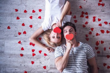 Güzel genç çiftin kırmızı kağıt kalpler tutarak ve kamera lyng katta ise bakarak Üstten Görünüm