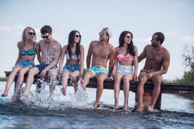 Mutlu arkadaş su ve Deniz kenarındaki iskelede otururken gülümseyen