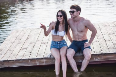 Mutlu çifte sarılma, söz ve Deniz kenarındaki iskelede otururken gülümseyen