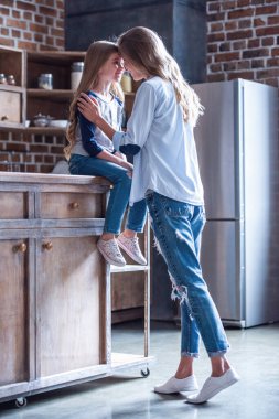 Sevimli küçük kız ve güzel annesi alınlarına ile dokunaklı ve birlikte mutfakta vakit ise gülümseyen