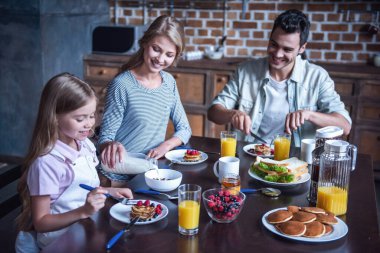 Mutlu bir aile söz ve birlikte mutfakta Kahvaltı yaparken gülümseyen