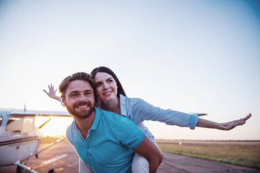 Güzel Romantik Çift uzakta arıyor ve yere yakın uçak kalkış üzerinde ayakta gülümseyen, kız Paketle