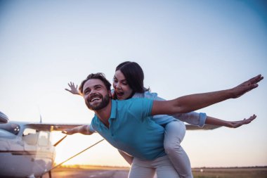 Güzel Romantik Çift uzakta arıyor ve yere yakın uçak kalkış üzerinde ayakta gülümseyen, kız Paketle