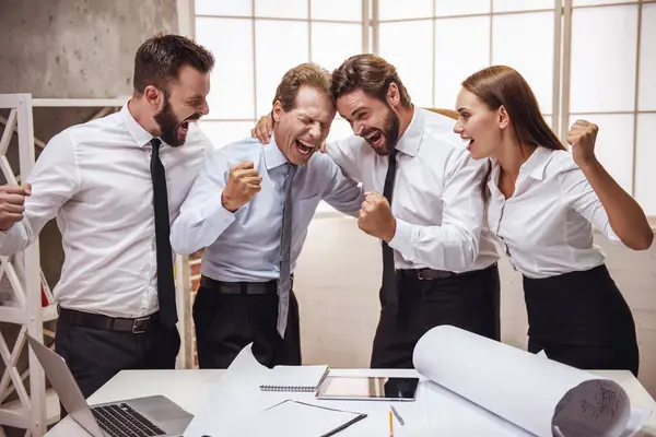 Successful business people are hugging and screaming with success while working in office