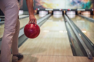 Bir kırmızı bowling topu atmak için hazır tutan adamın Resim kırpılmış