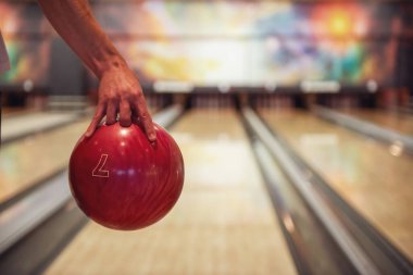 Adamın elini tutan bir kırmızı bowling topu atmak için hazır