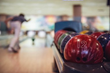 Adam ön planda renkli top kırmızı bir bowling topu atma