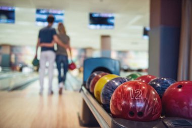 Güzel kız ve yakışıklı olan bowling topları tutan ve oynarken sarılma arkadan görünüm