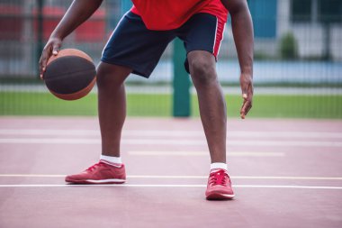 Basketbol sahasında oynayan yakışıklı basketbolcunun kırpılmış görüntüsü.