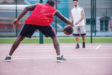 Yakışıklı basketbolcular açık havada basketbol sahası üzerinde oynuyorlar