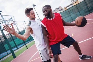Yakışıklı basketbolcular açık havada basketbol sahası üzerinde oynuyorlar