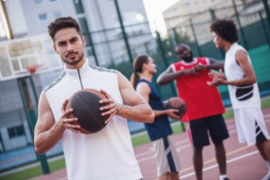 Yakışıklı basketbolcular konuştuğunuz ve açık havada basketbol sahası üzerinde gülümseyen, ön planda adam kameraya bakıyor