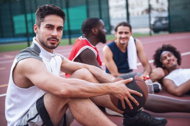 Yakışıklı basketbolcular konuşuyor ve basketbol sahası üzerinde açık havada maçtan sonra otururken gülümseyen