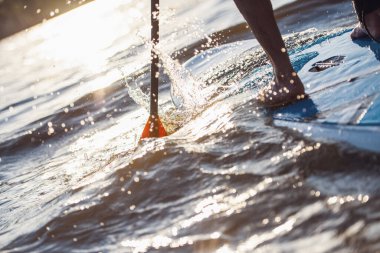 Yakışıklı genç Sup sörf Nehri üzerinde Resim kırpılmış, güneş batıyor