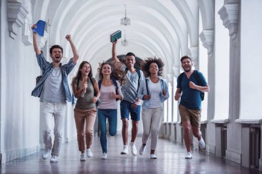 Güzel genç öğrenciler kameraya bakıyor ve Üniversitesi salonu çalıştırırken gülümseyen