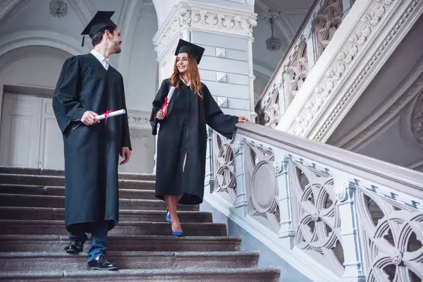 Successful Couple Graduates Academic Dresses Holding Diplomas Talking Smiling While — Stock Photo, Image