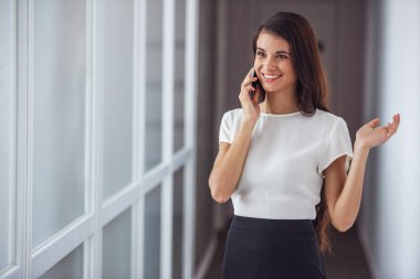 Güzel genç esmer kadın cep telefonda konuşurken ve Office dururken gülümseyen