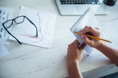 Ofiste çalışırken notları yapım resmi giysili yakışıklı genç işadamı kırpılmış görüntü