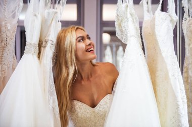 Çekici genç gelin modern düğün salonu gelinlik seçerken gülümsüyor