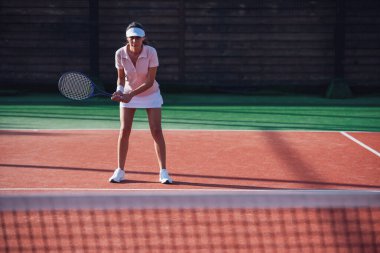 Güzel genç kız açık havada sahada Tenis oynarken tenis raketi tutuyor