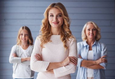 Güzel kadınlar Üretimi: anneanne, anne ve kızı kameraya bakarak ve çapraz kol ile ön planda anne ayakta iken gülümseyen