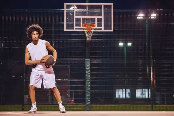Attractive basketball player is playing basketball outdoors in the evening