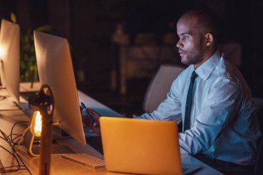 Yakışıklı Afro Amerikalı işadamı Klasik takım elbiseli akşam geç ofiste çalışırken bir bilgisayar kullanıyor