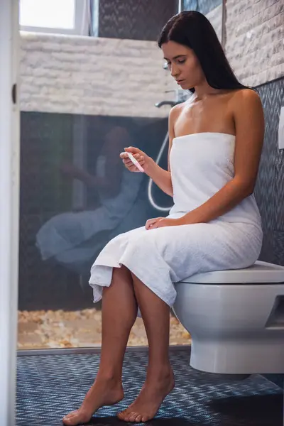 Attraktiv Ung Kvinna Handduk Håller Ett Graviditetstest Medan Sitter Toaletten — Stockfoto