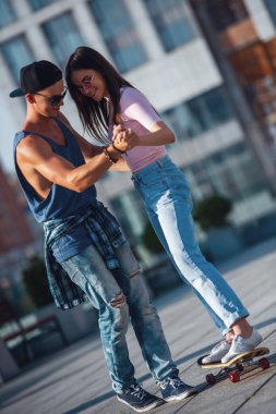 Şık genç çift zaman şehirde birlikte geçiriyor. Adam sevgilisini kaykay öğretiyor