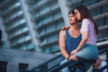 Şık genç çift sarılma ve şehirde yürürken gülümseyen