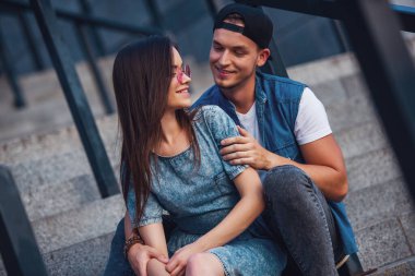 Şık genç çift sarılma, söz ve merdivenlerde otururken gülümseyen
