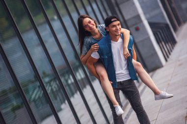 Şık genç çift eğlenceli yaşıyor ve açık havada yürürken gülen, kız pickaback oturuyor