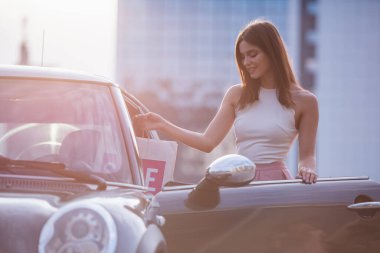 Güzel zarif esmer kız arabasına almak ve gülümseyen