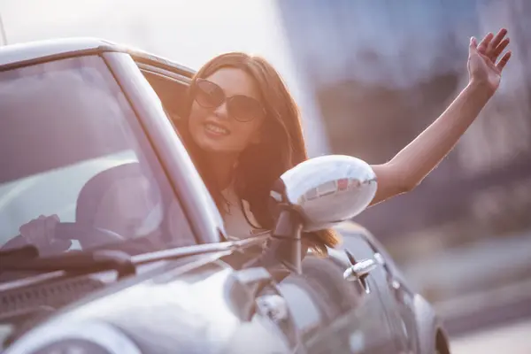 Beautiful Brunette Girl Waving Smiling While Driving Her Car Stock Image
