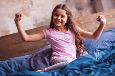 Sevimli küçük kız germe, kameraya bakıyor ve sabahları yatakta yatan süre gülümseyen