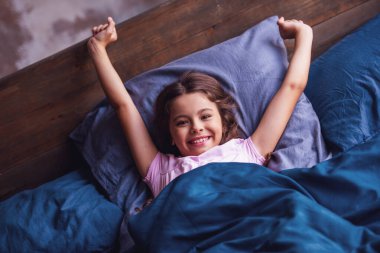 Sevimli küçük kız germe, kameraya bakıyor ve sabahları yatakta yatan süre gülümseyen