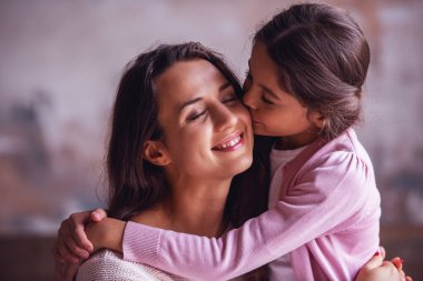Güzel anne ve kızı sarılma, kız onu yanak içinde öpüyor iken anne gülümsüyor