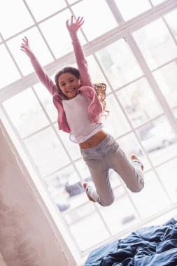 Güzel küçük bir kız evde yatakta atlama sırasında eğleniyor