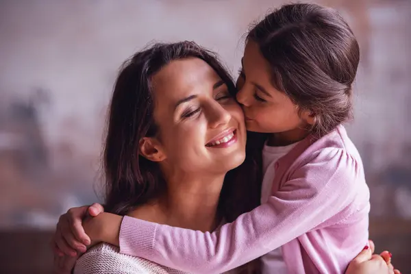 漂亮的妈妈和女儿在拥抱 妈妈在微笑 而女孩在亲吻她的脸颊 — 图库照片