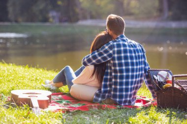 Arkadan görünüşü güzel genç çift ekose Park üzerinde dinlenme süre sarılma