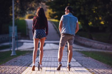 Arkadan şık genç çift sürme scooter parkta görünüşü