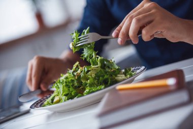 Kafede salata yiyen genç adam görüntüsü.