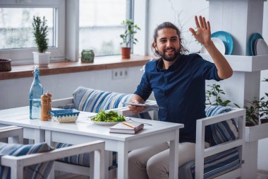 Uzun siyah saçlı yakışıklı genç bir garsona sallayarak ve kafede yemek yerken gülümseyen bir dijital tablet tutuyor