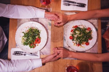 Genç çift elele tarihlerine sırasında bir restoranda, üstten görünüm kırpılmış