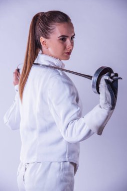 Çekici kadın fencer koruyucu giyim gri arka plan üzerinde bir silah düzenliyor