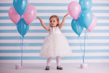 Kabarık beyaz elbiseli sevimli küçük kız elleri kadar Balonlar, ışık arka plan üzerinde yakın dururken yükselterek