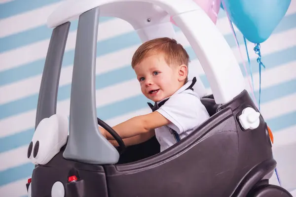 Niedlicher Kleiner Junge Lächelt Während Spielzeugauto Sitzt Auf Hellem Hintergrund lizenzfreie Stockfotos