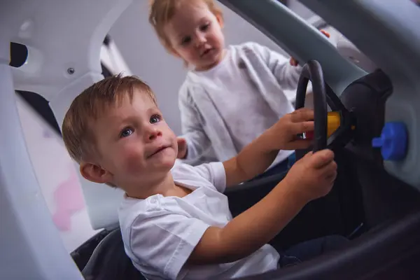 Niedliche Kinder Spielen Zusammen Junge Sitzt Spielzeugauto Mädchen Steht Daneben Stockfoto
